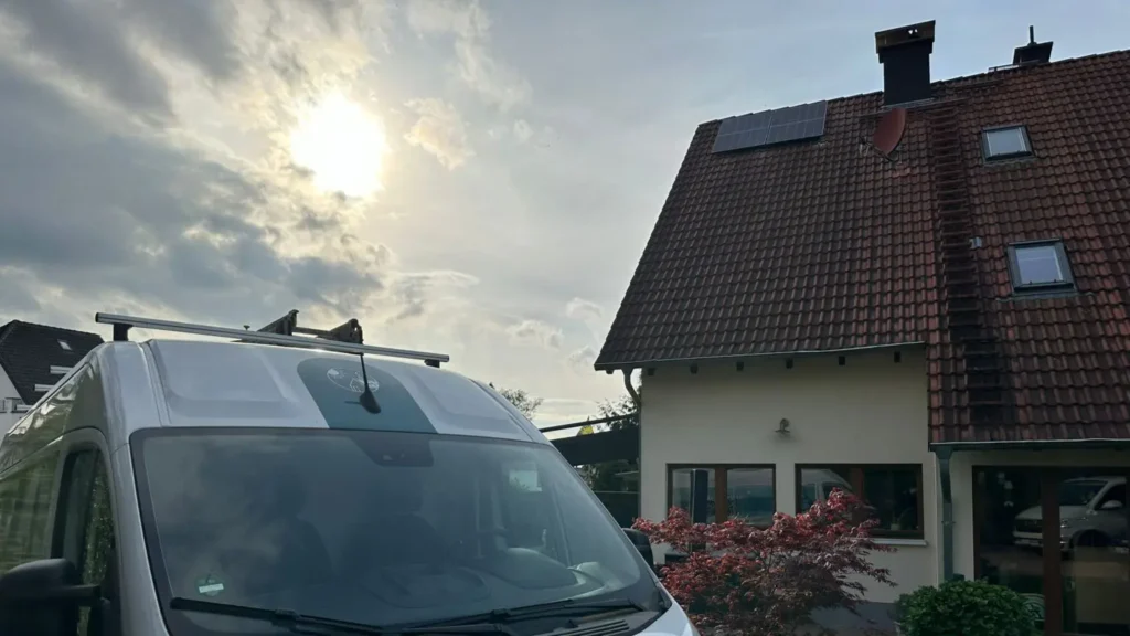 Aufnahme einer Photovoltaikanlage, die auf dem Dach eines Gebäudes montiert ist, im Vordergrund das Firmenfahrzeug der Honczek Solartechnik