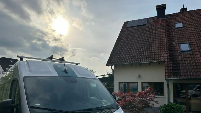 Aufnahme einer Photovoltaikanlage, die auf dem Dach eines Gebäudes montiert ist, im Vordergrund das Firmenfahrzeug der Honczek Solartechnik
