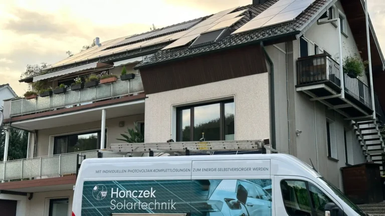 Firmenfahrzeug der Photovoltaik-Firma Honczek Solartechnik vor einem Gebäude mit Solarpaneelen auf dem Dach