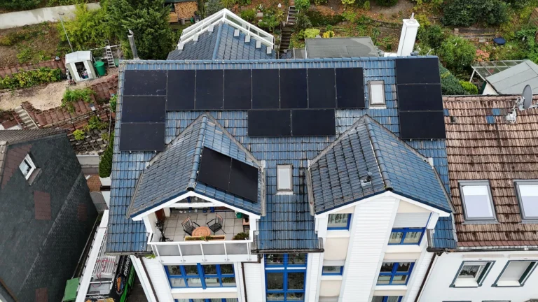 Luftaufnahme einer Photovoltaikanlage, die auf dem Dach eines mehrstöckigen Gebäudes montiert ist